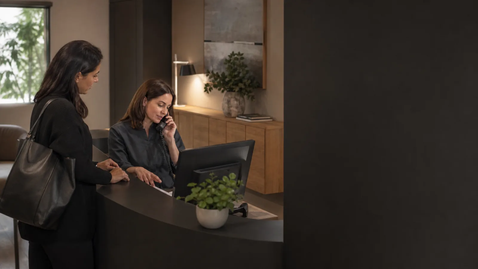 Una segretaria accoglie una paziente mentre gestisce una telefonata nello studio